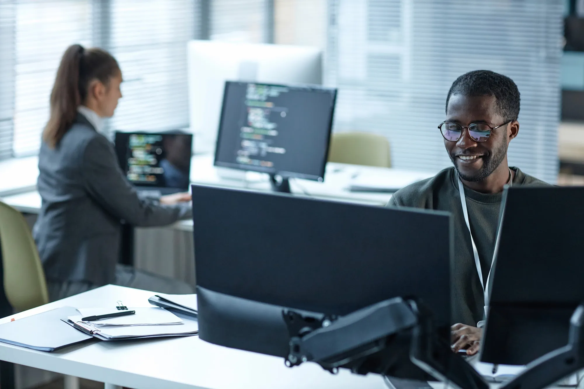 Smiling IT support technician working at a computer in a busy Greensboro, NC office