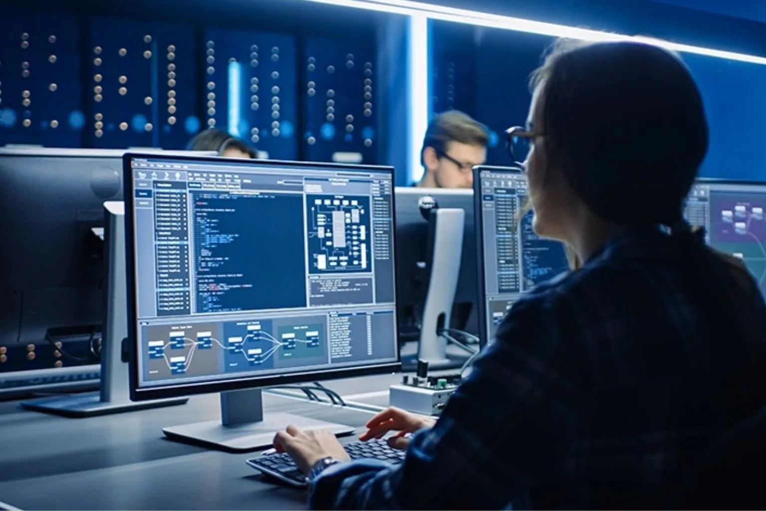 Security analyst monitoring systems on several screens in an operations room