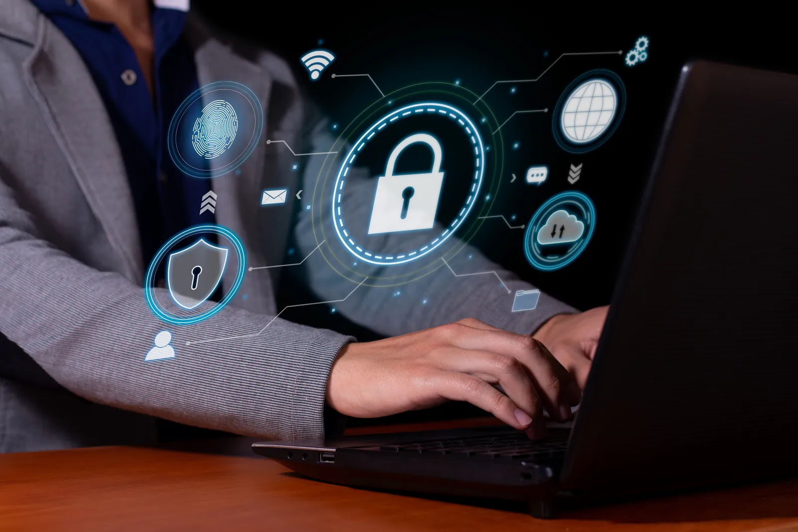 Business user on a laptop with padlock, fingerprint and shield security icons