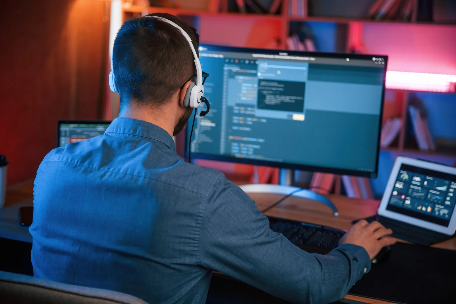 Help desk technician with a headset reviewing a business system on two screens