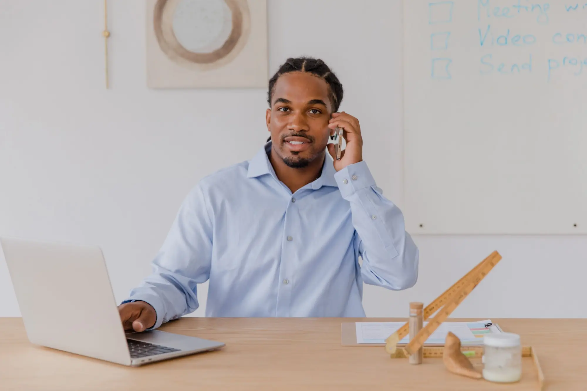 Business owner on a phone call while working on a laptop at his office desk