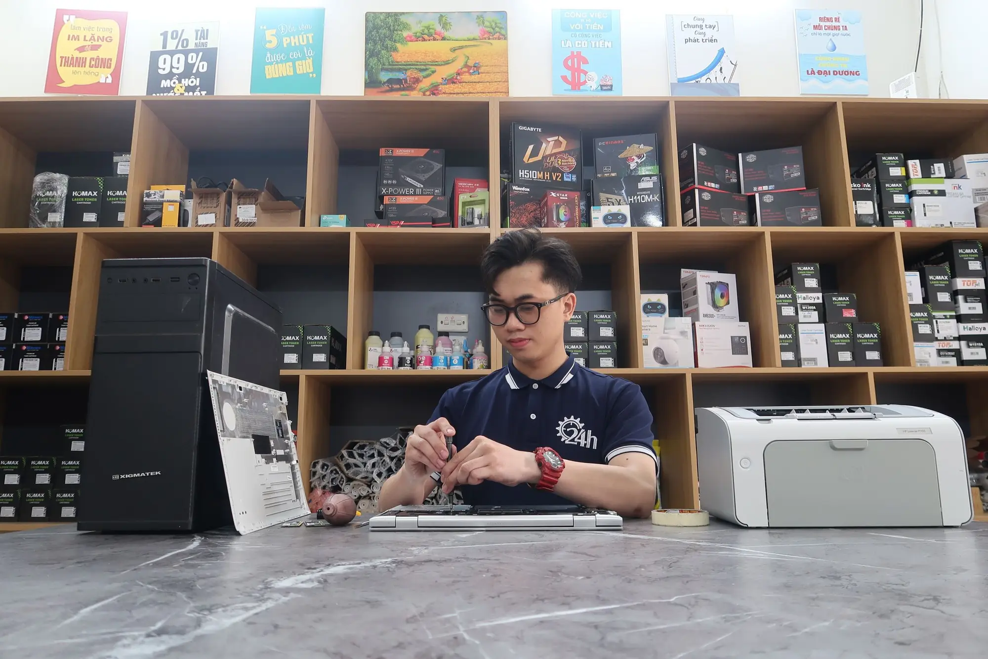 Technician repairing a desktop computer at a workbench in a computer store
